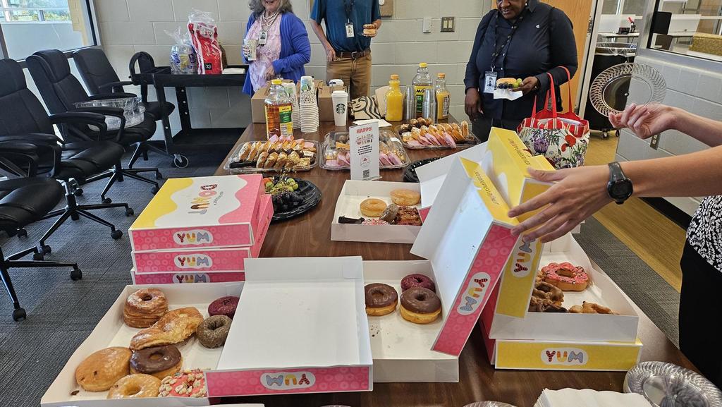 Sweet boxed treats and juices and fruit on table in conference room with teachers. 