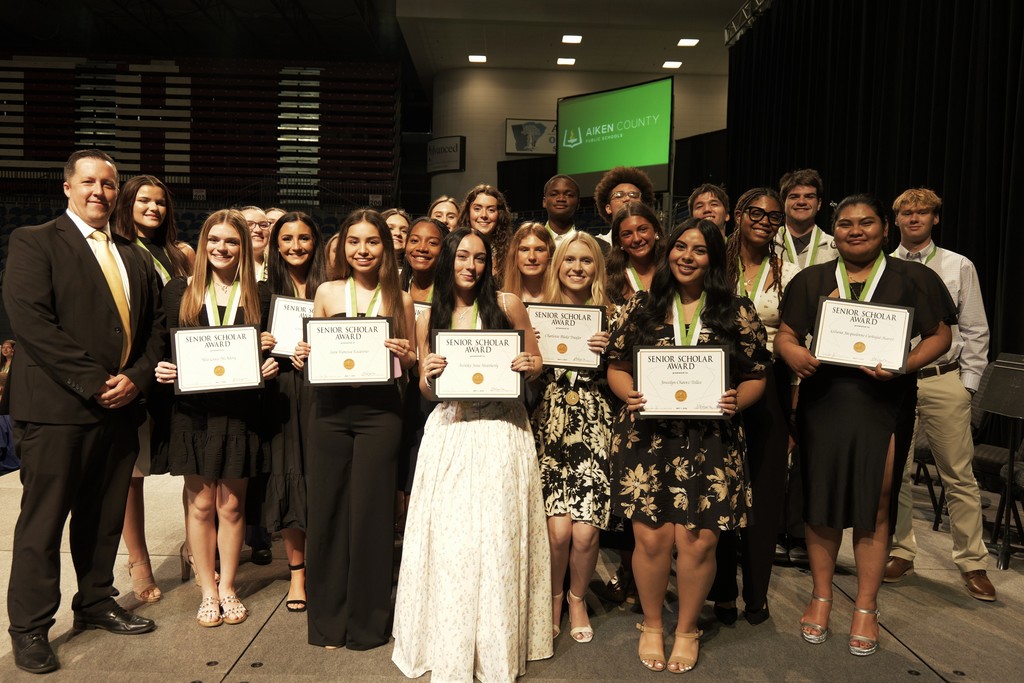 Principal Casey Rogers poses with his students on stage.