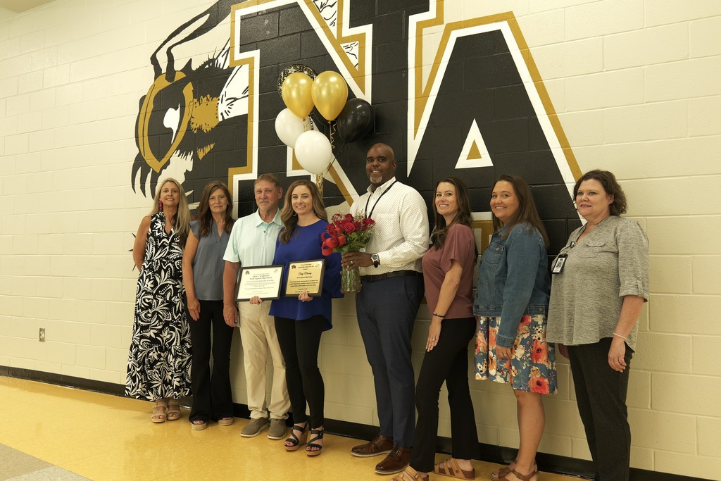 Tracy posted with staff in front of North Augusta High logo.
