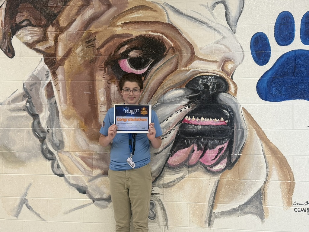 Evan Hup in front of bulldog mural holding a certificate