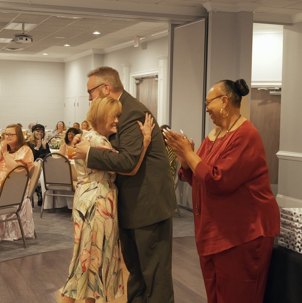 Two adults embracing during a retirement banquet.