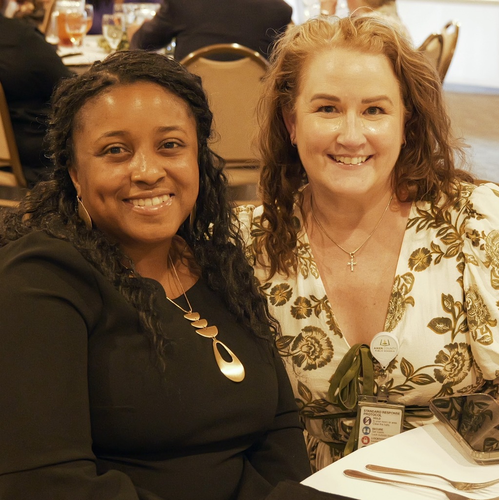 Two women smiling and posing for a photo during a retirement banquet.