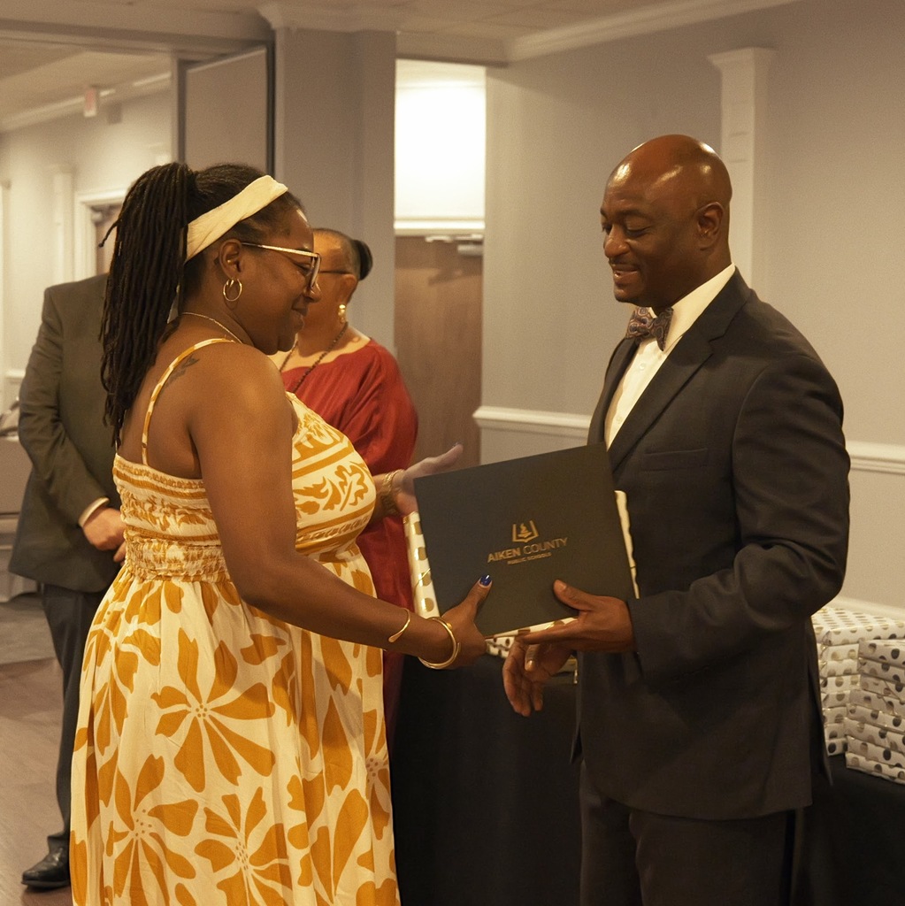 Retiree receiving a certificate and gift from Dr. Corey Murphy, Superintendent.