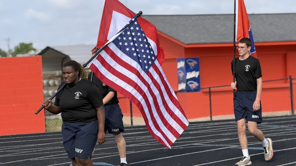 Students running holding flags on a track.