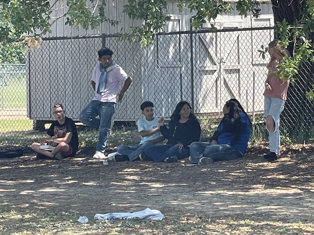8th grade students resting in the shade during a picnic.