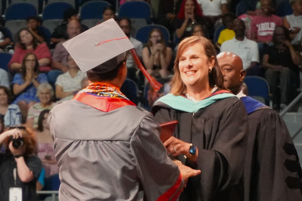 ASA Principal Martha Messick gives a diploma to an male student. 