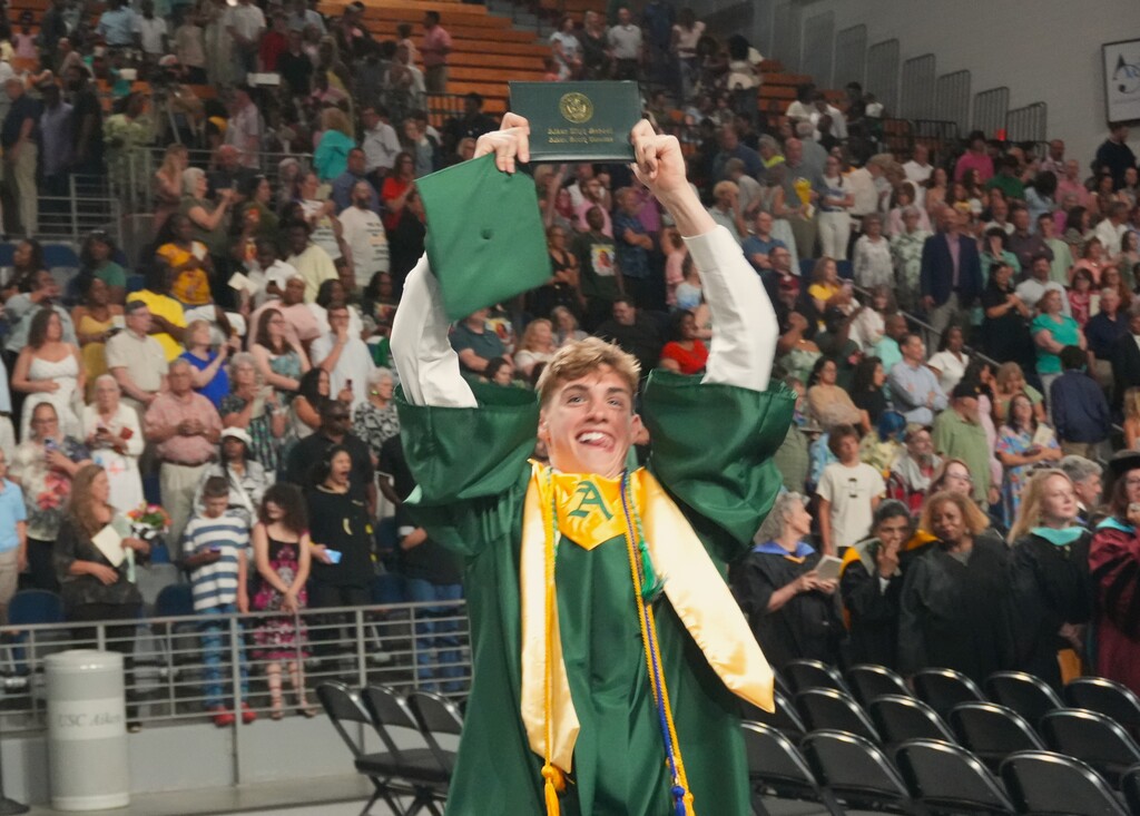 An Aiken High graduate holds up his diploma.