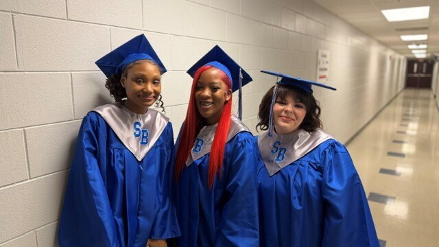 Three femail graduates posing for a photo while lining for Silver Bluff High's graduation.