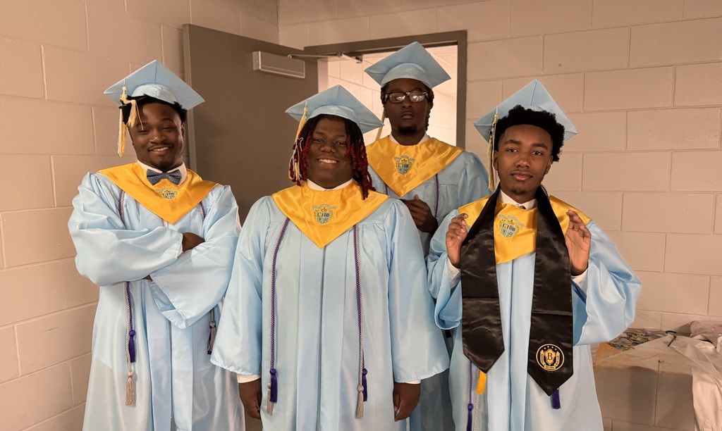 Four young men smiling and posing for a photo in their caps and gowns showing happiness and excitement.