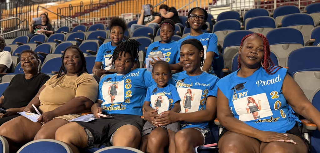 A family showing their support for their graduate by wearing matching t-shirts and big smiles.