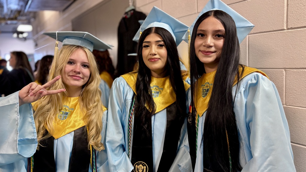 Three girls posing for a picture in their caps and gowns.
