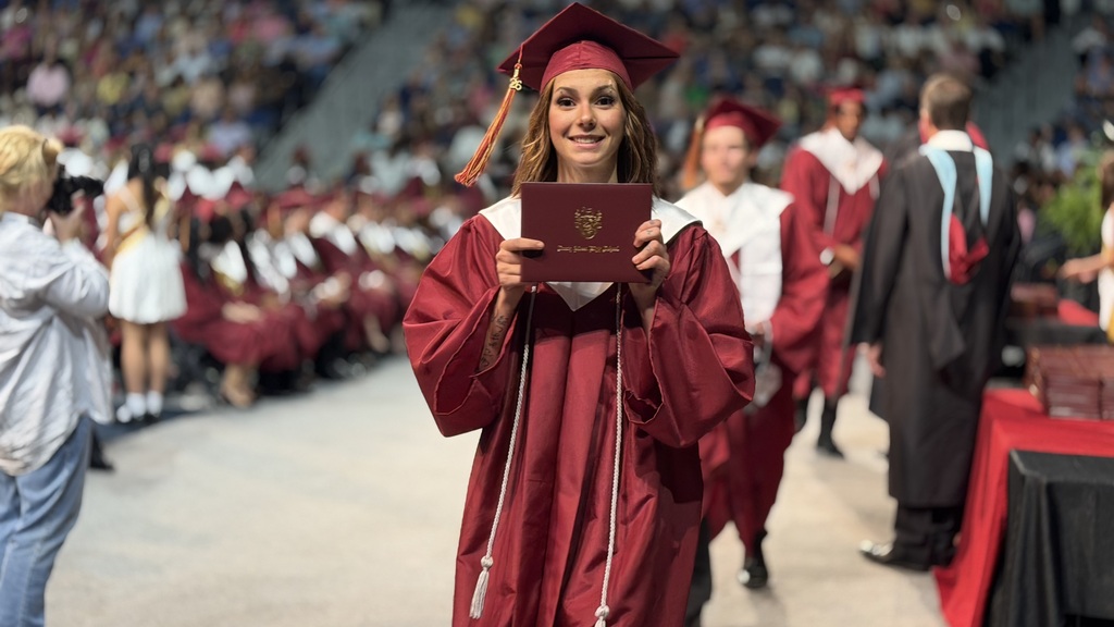 SAHS graduate walking with their diploma.