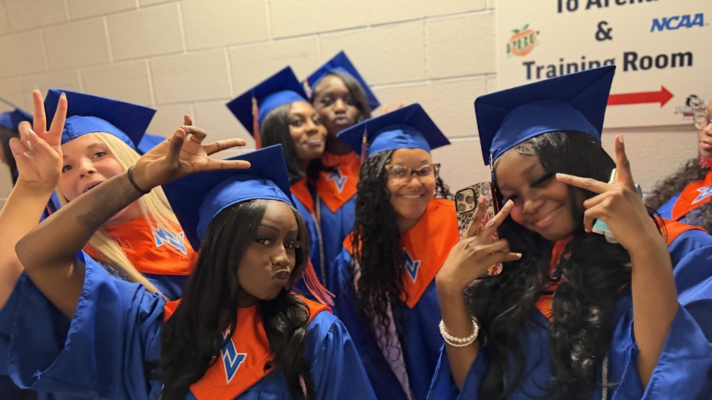 Graduates posing for a photo in their gowns prior to graduation.