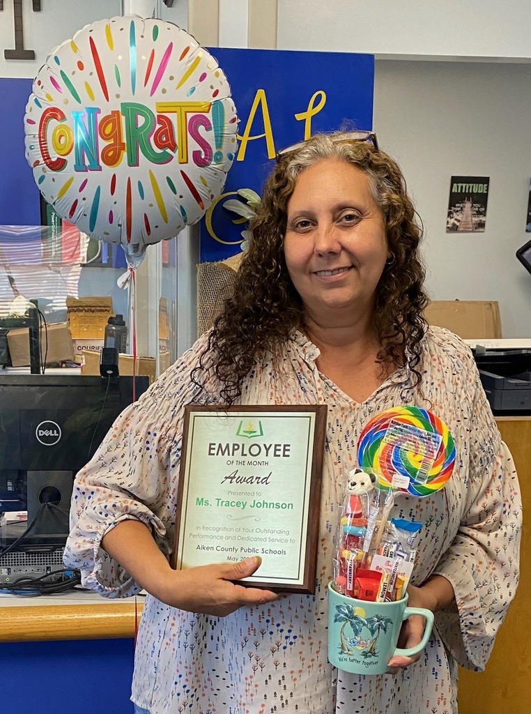 Ms. Tracey Johnson holding an employee of the month award.
