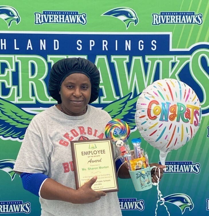 Ms. Sharon Morton holding an employee of the month award.