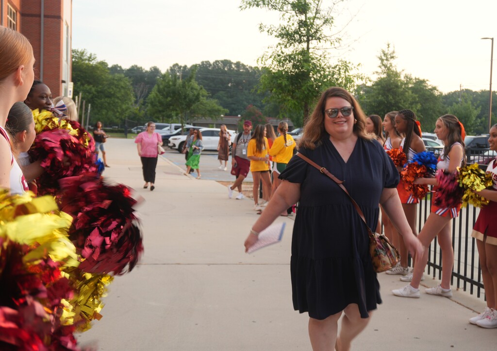 A new teacher walks into Aiken County Ignite orientation through a tunnel of cheerleaders.