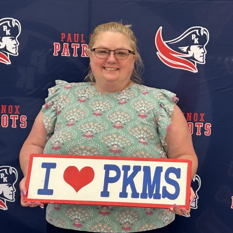 teacher holding "I love PKMS" sign