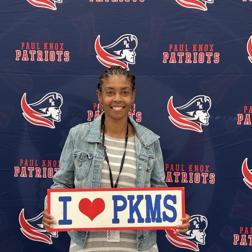 teacher holding "I love PKMS" sign