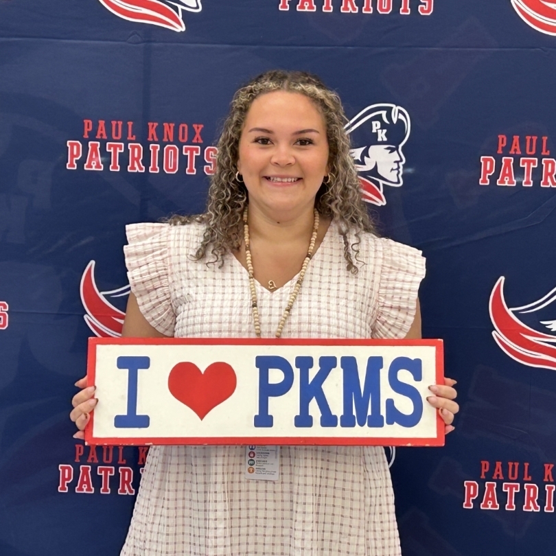 teacher holding "I love PKMS" sign