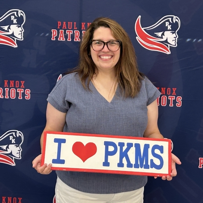 teacher holding "I love PKMS" sign