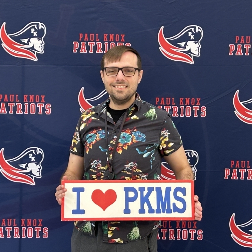 teacher holding "I love PKMS" sign