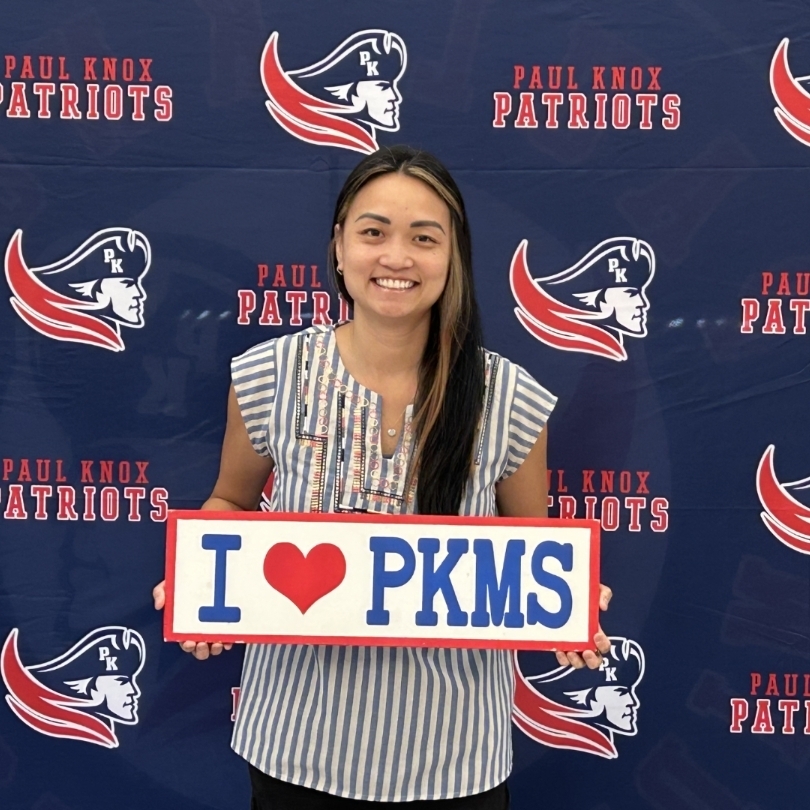 teacher holding "I love PKMS" sign