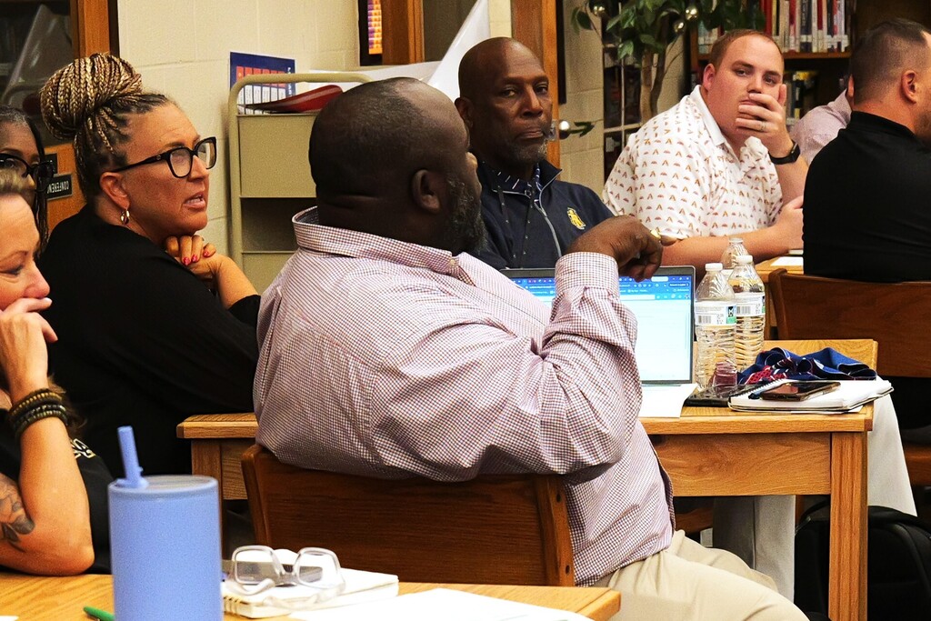A principal engages in a discussion with Dr. Amy Edwards and the group.