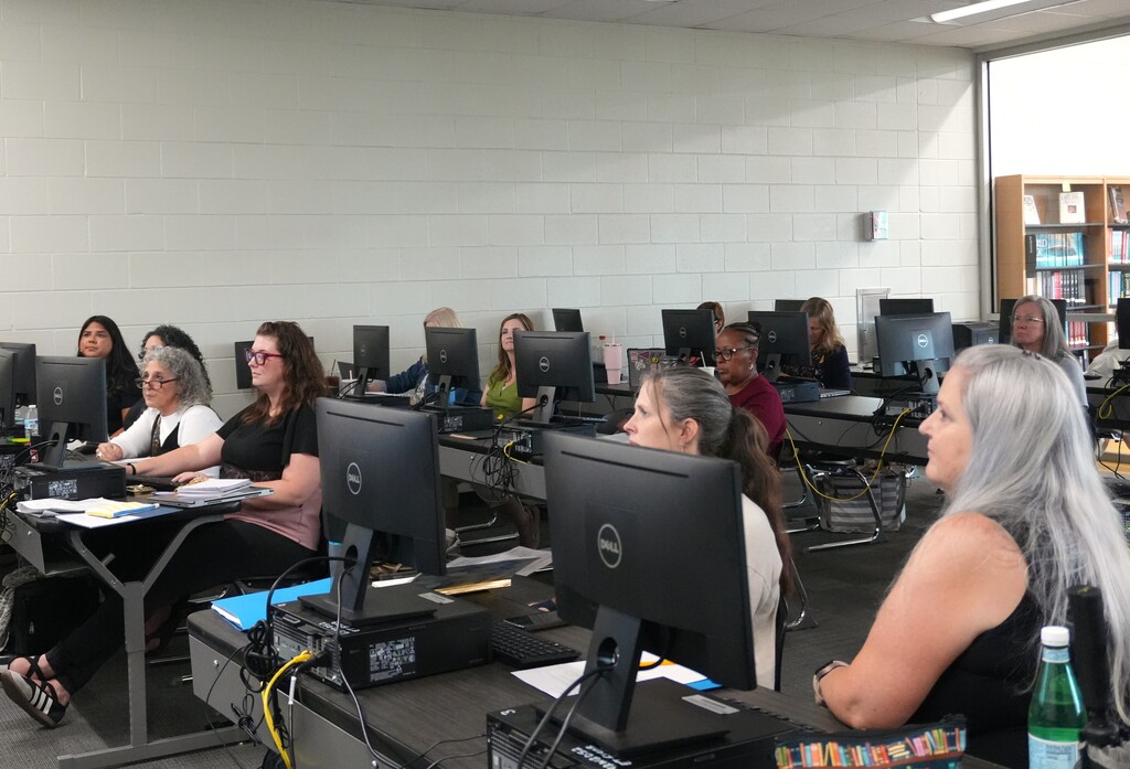 Multilingual Learning teachers sit at a computer lab and watch a presentation. 
