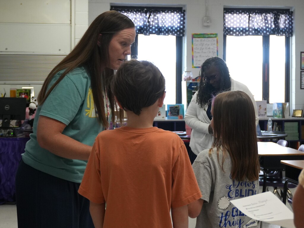 Two elementary school students speak with their new teacher.