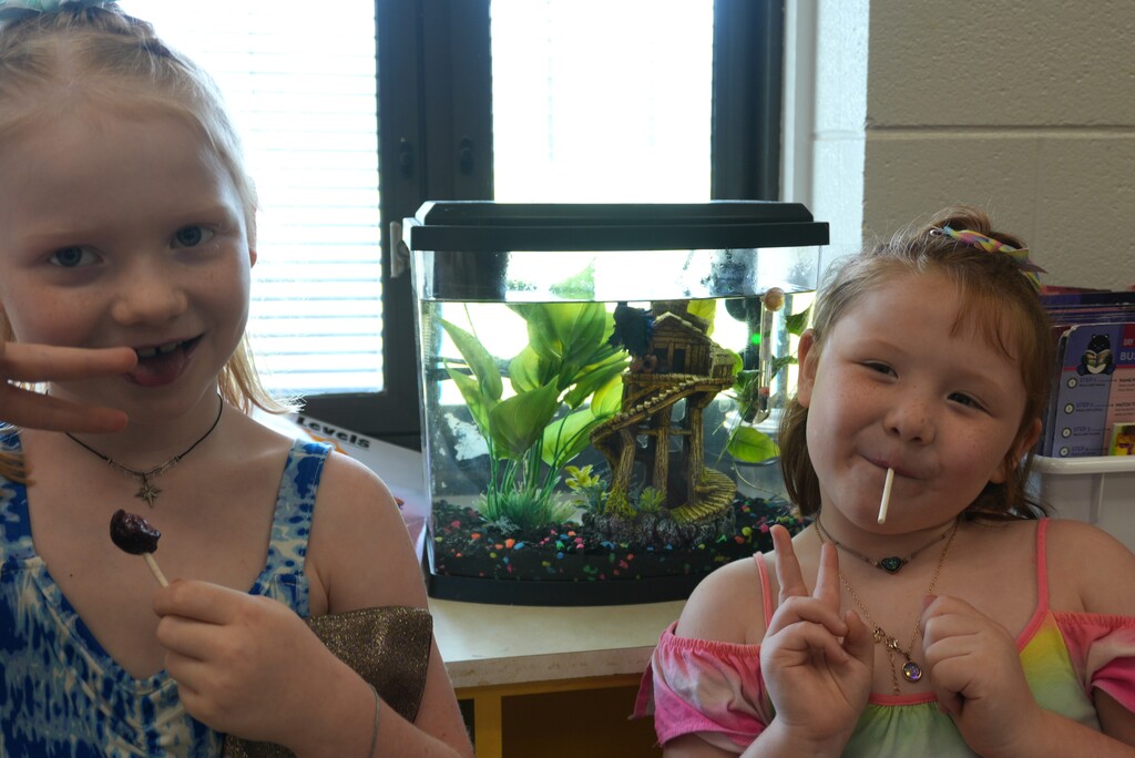 Two elementary school students pose with a class fish, Bluey. 