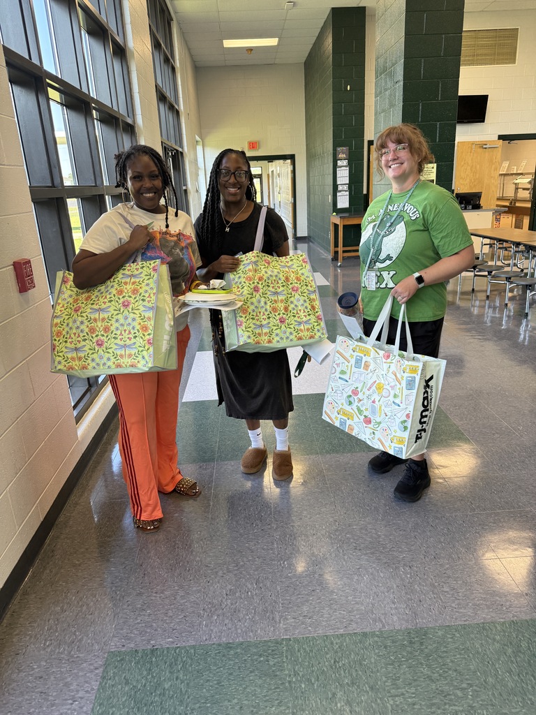 three people smiling and holding bags 
