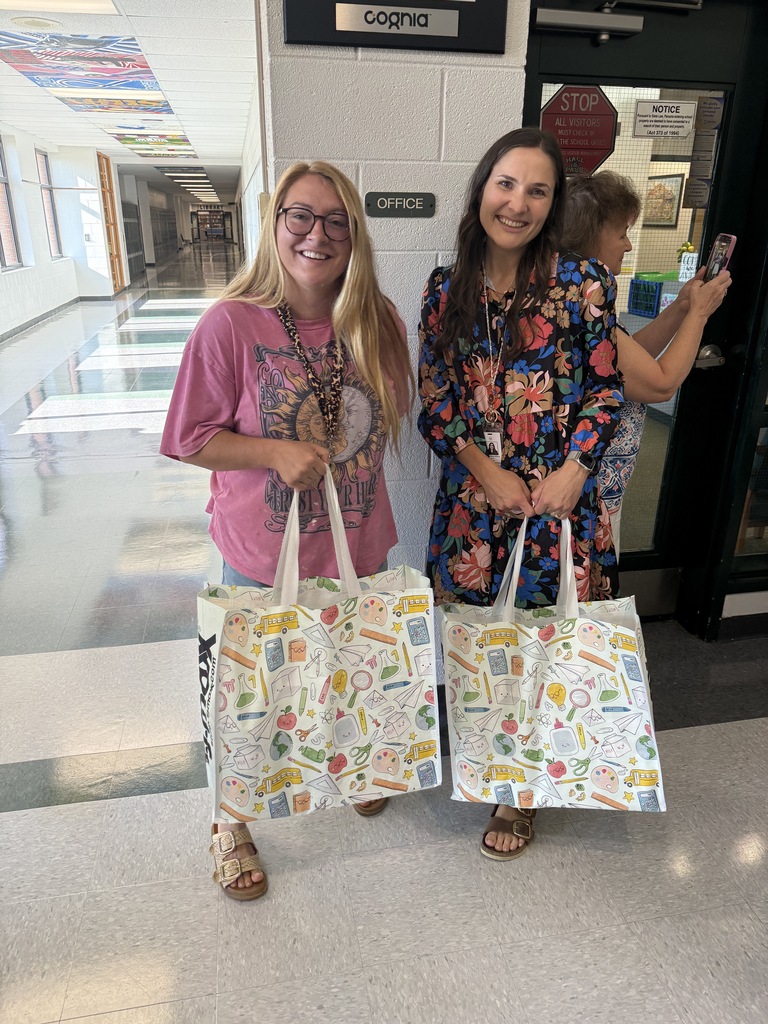 two people smiling and holding bags 
