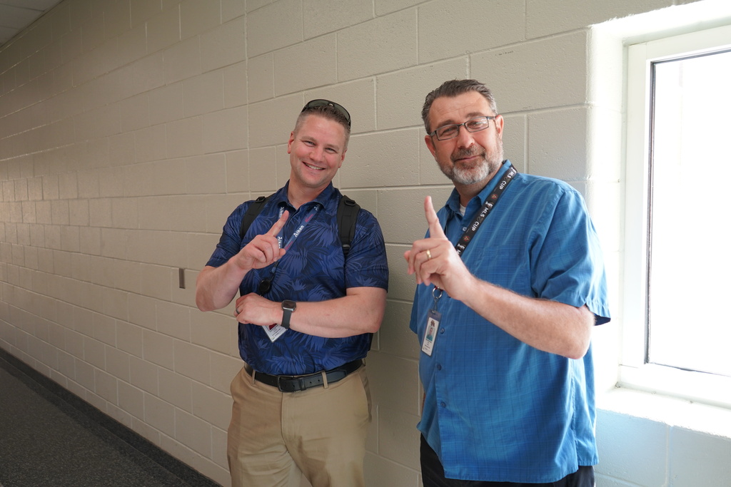 "Teacher holding up the number 1 with their index finger." 