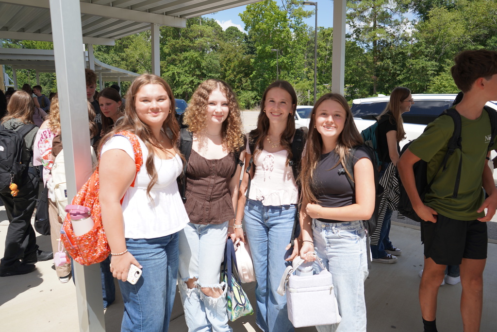 "4 girls outside in car line smiling."