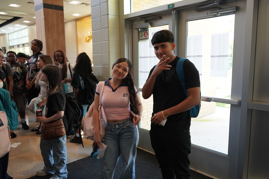 "Girl and boy student in front of doors smiling. "