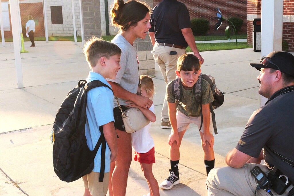 Students speaking with the school safety officer after getting out of the car.