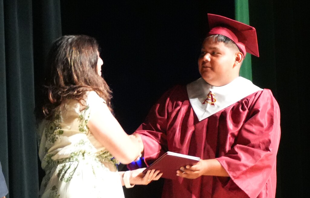Graduates shake hands with school and district leadership.