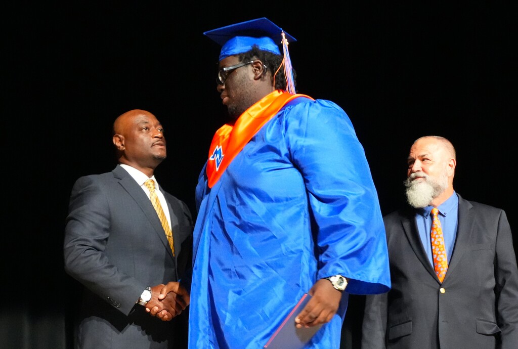 Graduates walk across the stage to receive their diploma.