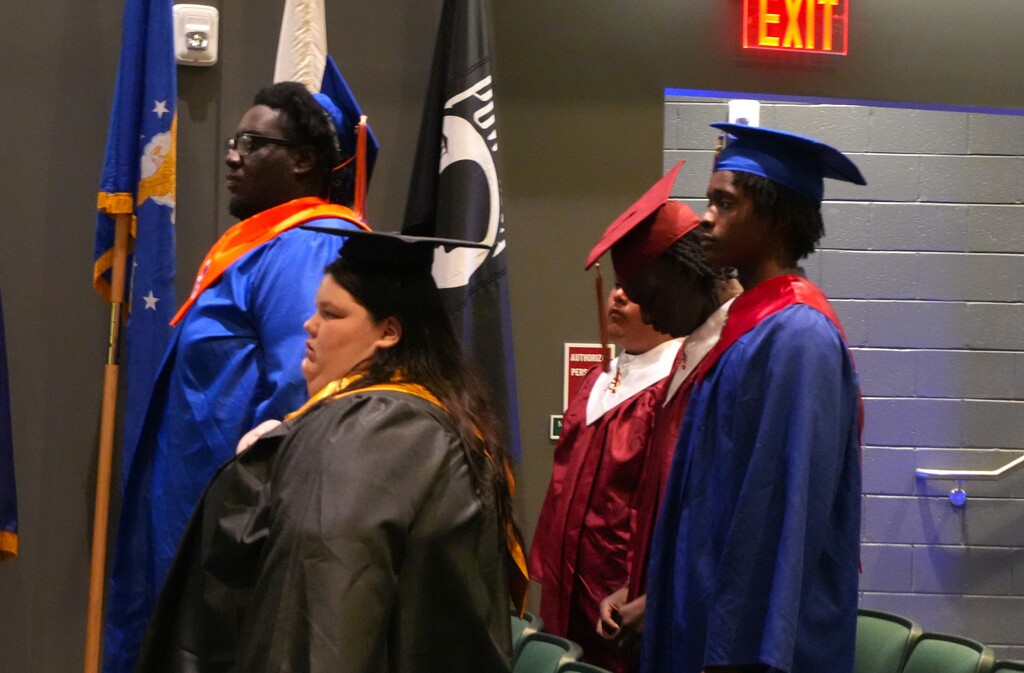 Graduates stand in cap and gown during their ceremony.