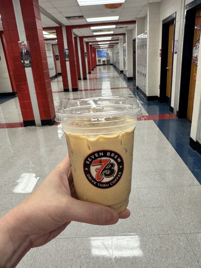 person holding iced coffee in school hallway