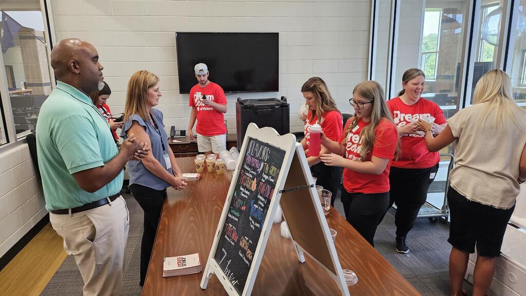 "Team of volunteers with teachers in breakroom serving coffee."