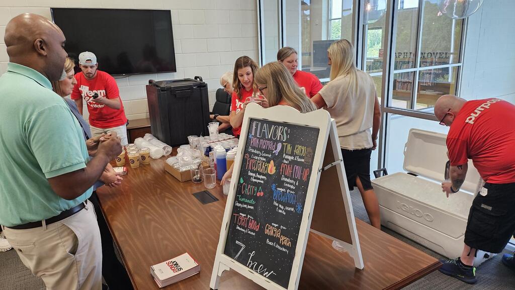 "Team of volunteers with teachers in breakroom serving coffee."