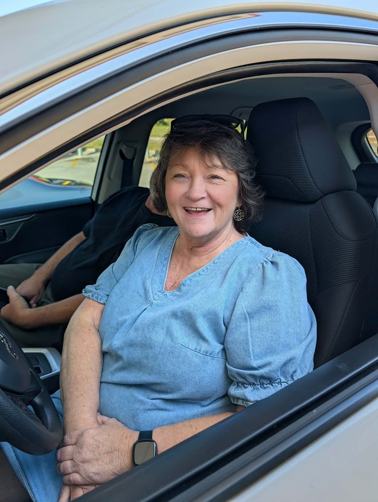Woman in car smiling.