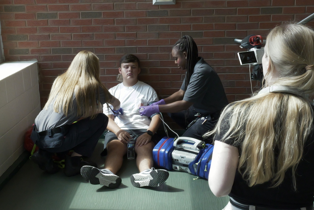 Camera pointed at student being attended to by emergency responders.