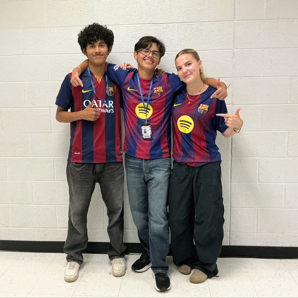 Two male and one female students wearing soccer jerseys
