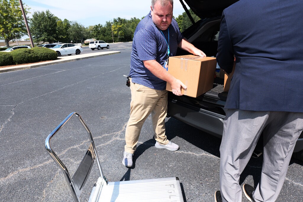 A man unloading a box of donation items onto a cart.