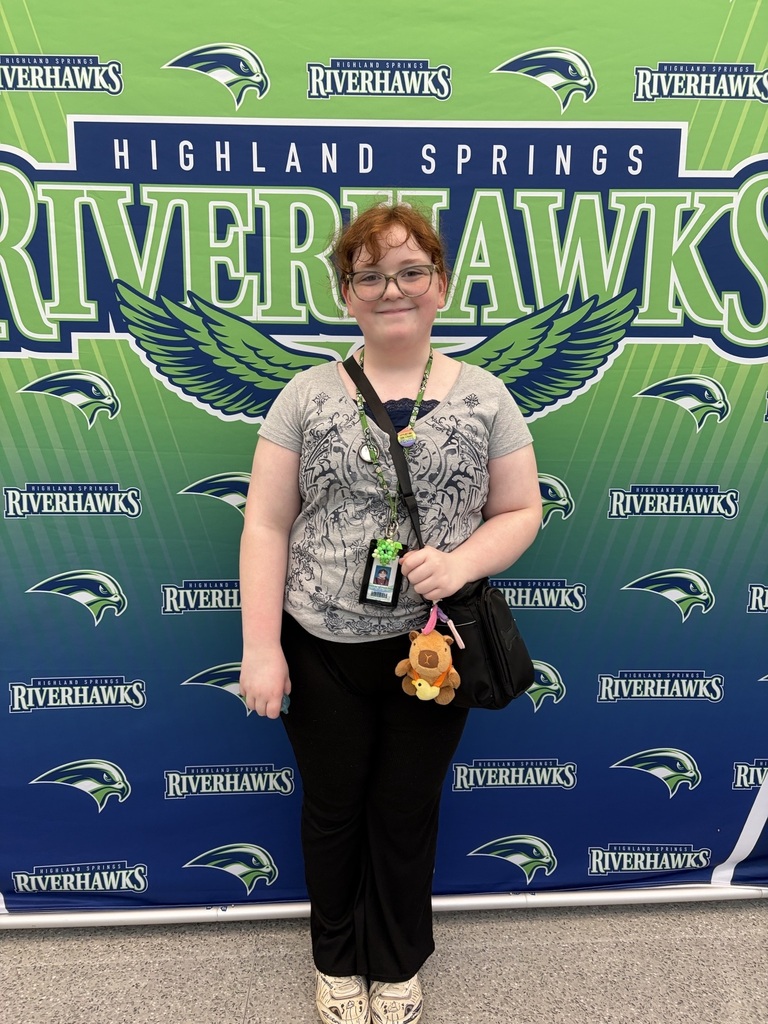 Student posing in front of Riverhawk bannr