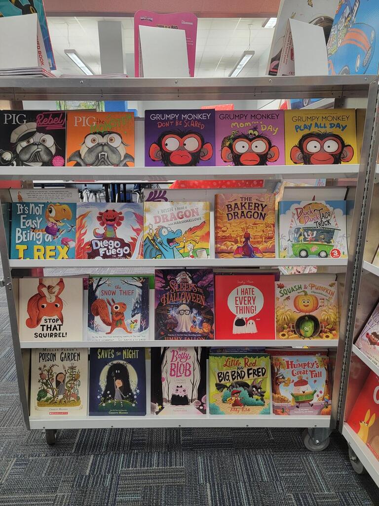 A metal shelf in a library displays multiple children's books on various topics, some featuring animals.