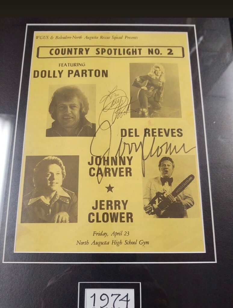 Displayed is a framed yellow poster from 1974 with a black border. The poster features several people.
