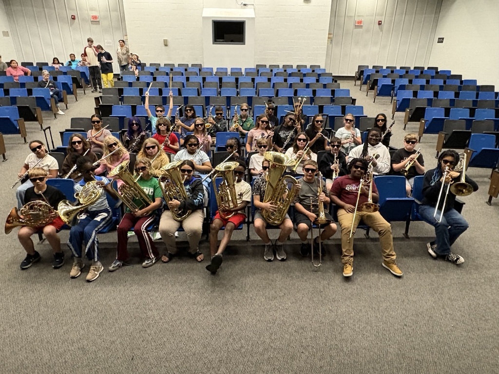 students sitting in an auditorium with their instruments